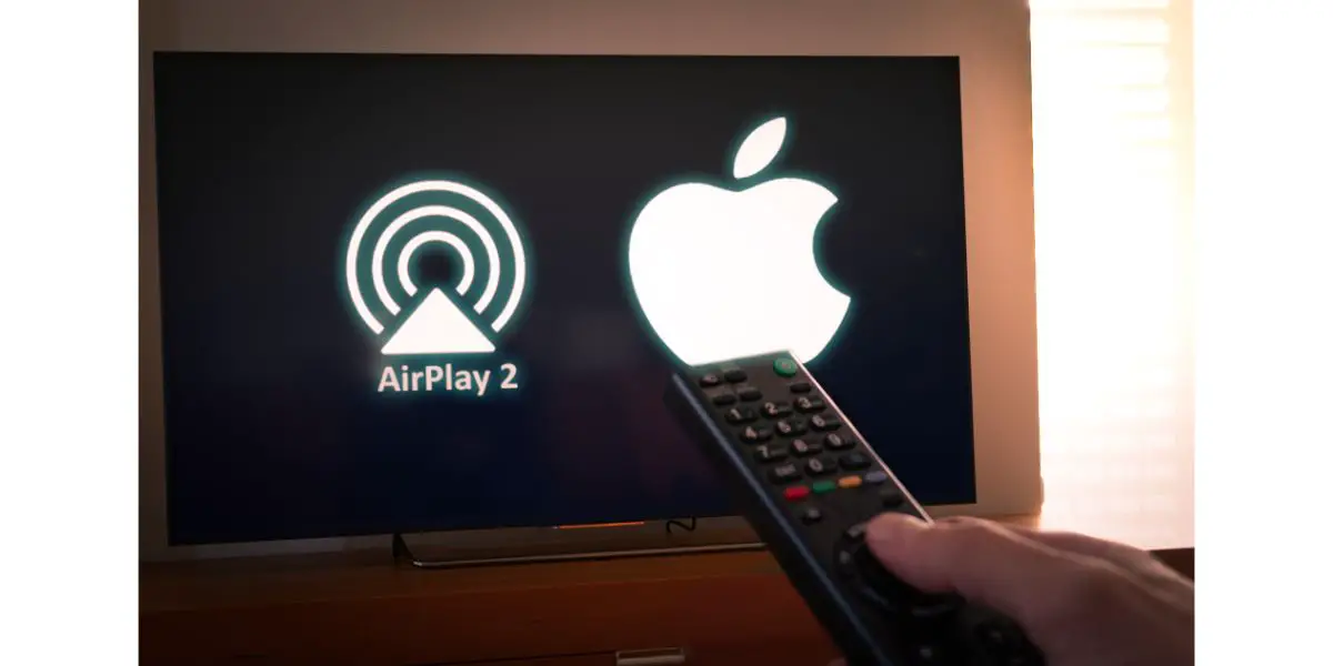 Depositphotos_237056396_L Man holds a remote control With an apple and airplay 2 logo on TV screen. In 2019 TV manufacturers like Samsun, LG and Vizio have announced AirPlay 2-enabled