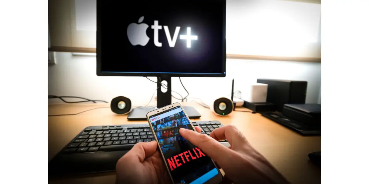 Depositphotos_253238414_L Man holds a smartphone with netflix app and a Pc with the new Apple TVplus on screen on the background. Apple TV is set to compete with other video streaming sub