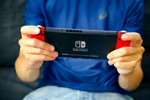 Depositphotos_278926132_S Man playing Nintendo Switch video game console