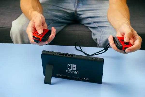Depositphotos_294825028_S Man playing Nintendo Switch video game console on the couch