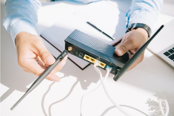 Depositphotos_310724328_S Cropped view of businessman adjusting antenna of router