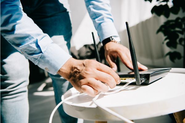 Depositphotos_310724450_S Cropped view of businessman plugging router on white table