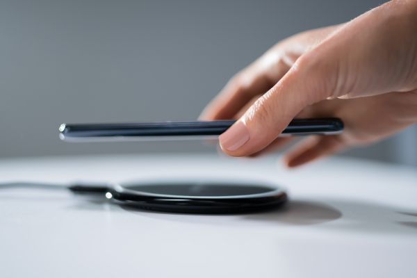 Depositphotos_331262388_S Woman Charging Smartphone Using Wireless Charging Pad At Home