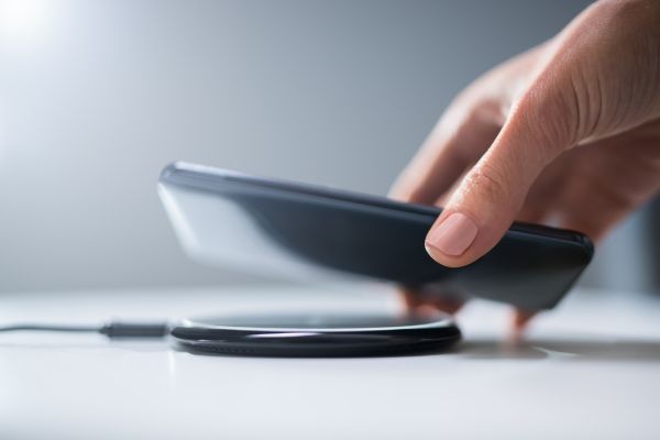 Depositphotos_333693080_S Woman Charging Smartphone Using Wireless Charging Pad At Home