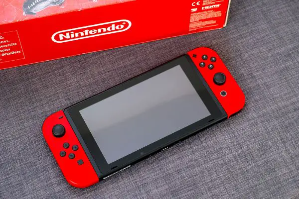 Depositphotos_386256878_S Nintendo Switch video game console and Nintendo red box. Gray background