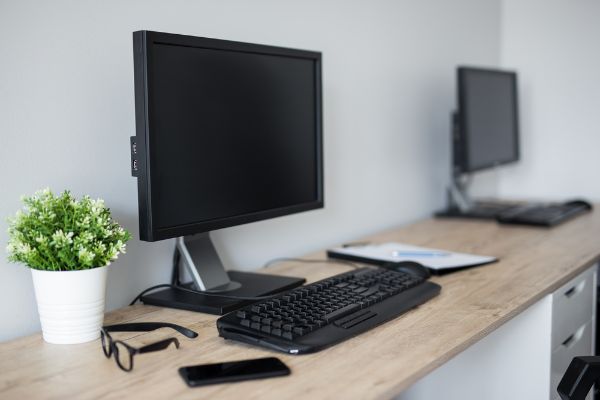 Depositphotos_386771772_S Computers with blank screens on wooden table in modern office