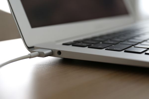 Depositphotos_388537718_S Modern laptop charging on wooden table,