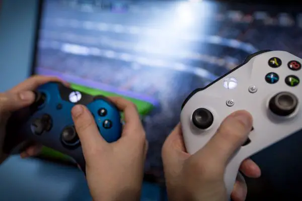 Depositphotos_415587488_S Xbox one s gamepad, game console, kid holding in his hands. Blurred background view and gaming concept.