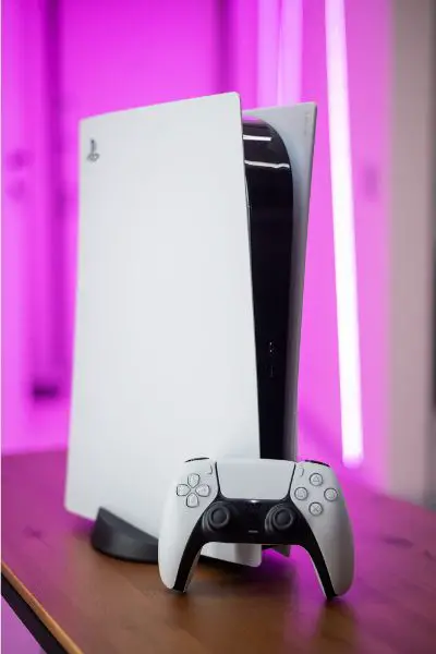 Depositphotos_431551702_S The new Sony gaming console PlayStation 5 and the DualSense controller in a pink neon color light (1)