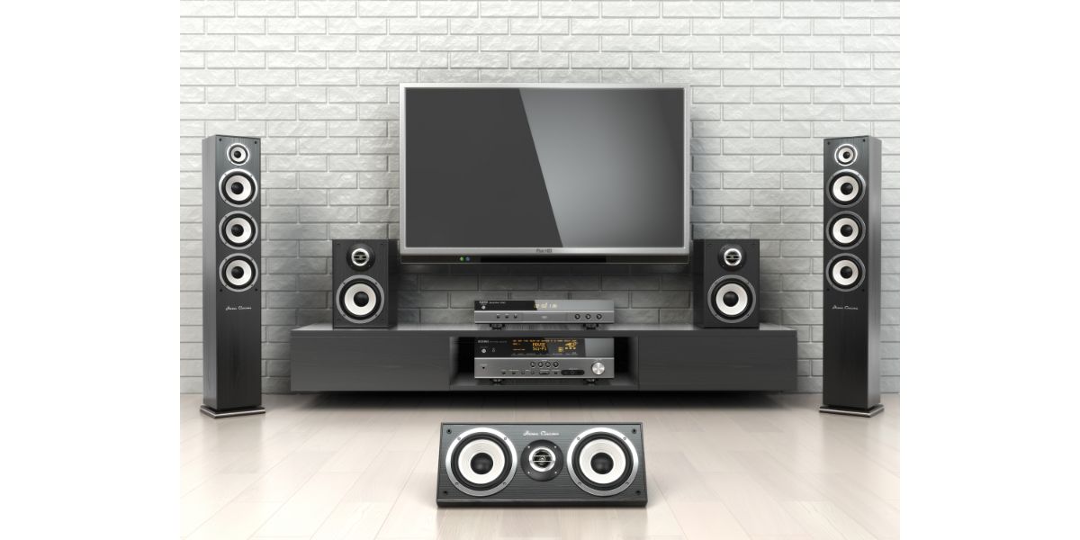 Depositphotos_61918939_L Home cinema system. TV, oudspeakers, player and receiver on wooden floor with concrete background