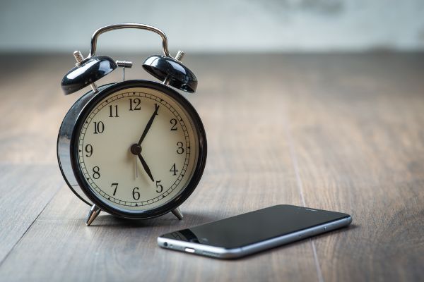 Depositphotos_70345739_S Black vintage alarm clock with phone on a wooden floor