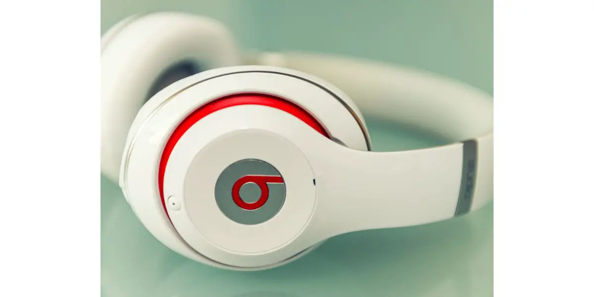 white Beats studio headset with red on greenish background with selective focus on part of headset